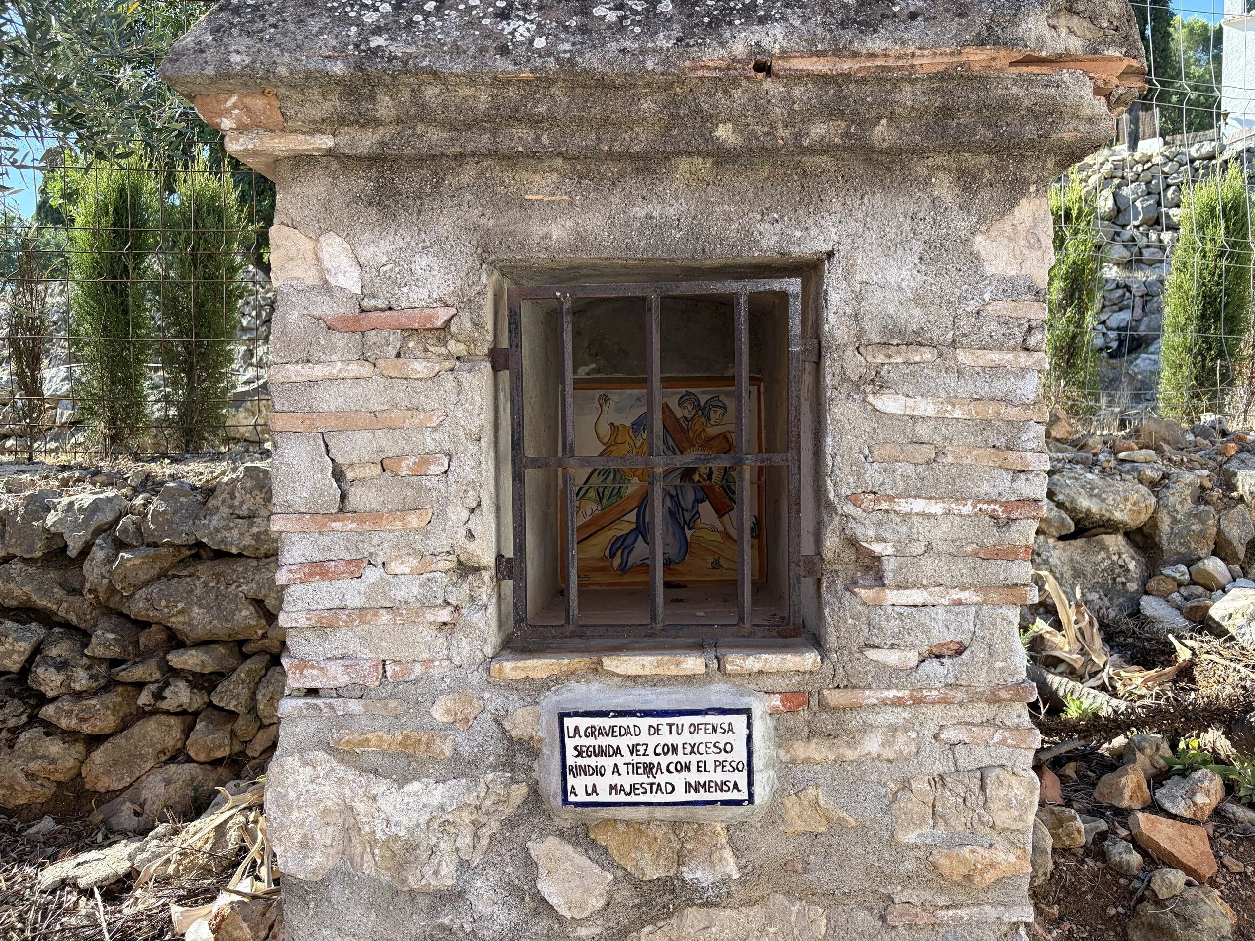 One of the Stations of the Cross on the old Calvary path: a painted tile of Jesus falling under the cross for the second time, behind iron bars