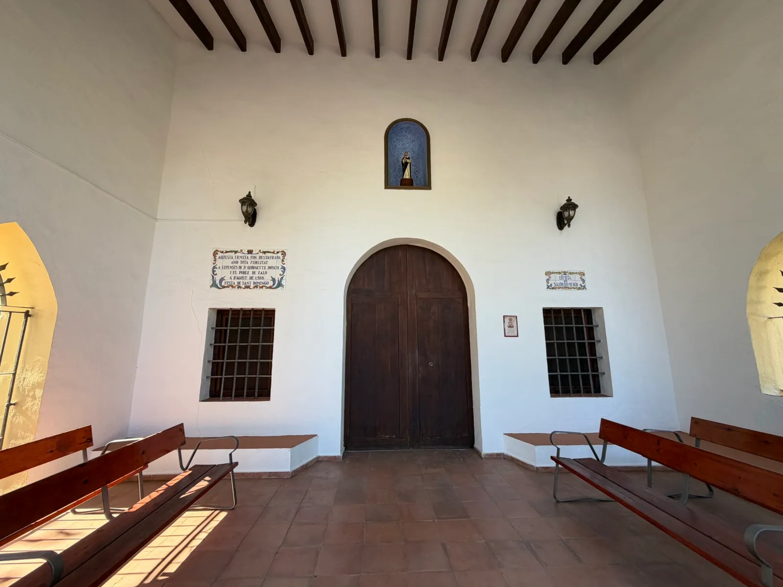 The porch of the Ermita, with wooden benches and the door to the chapel