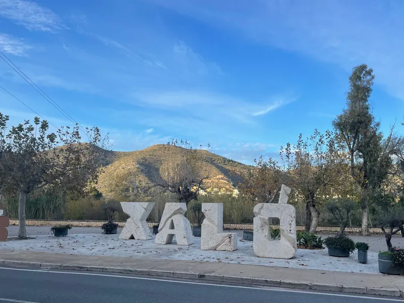 The carved stone letters spelling XALÓ, with the valley's hills behind them